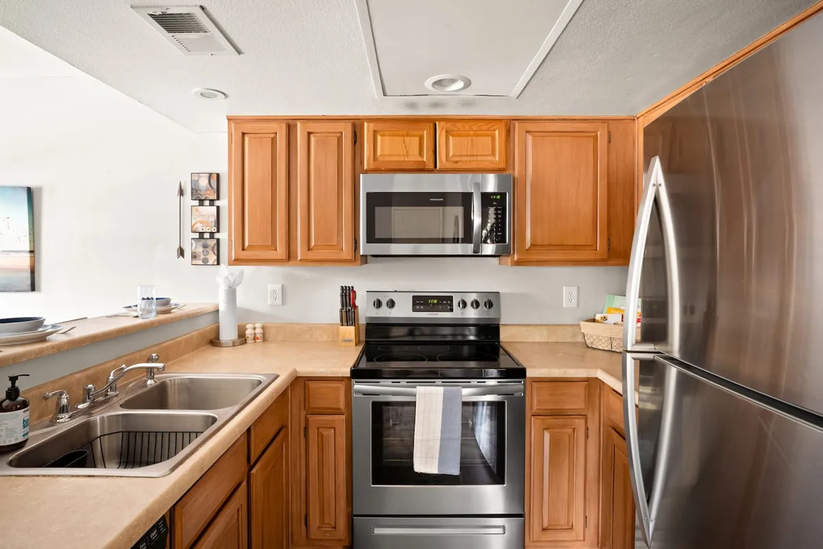 A warm and welcoming kitchen featuring stainless steel appliances, wood cabinetry, and ample countertop space. The layout is designed for both efficiency and comfort, with all the essentials visible for easy meal prep and entertaining.