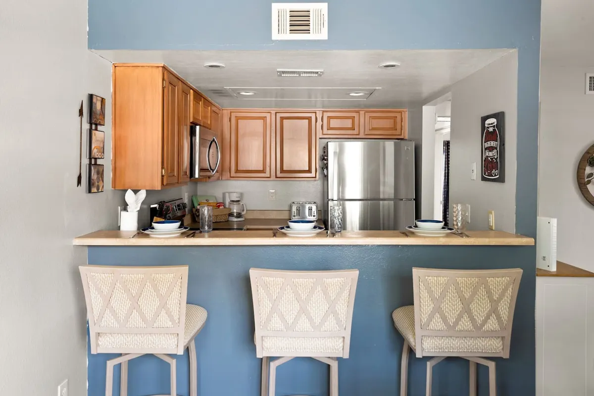 A spacious kitchen with a central island surrounded by bar stools, sleek appliances, and ample cabinetry. The island invites casual dining or socializing while preparing meals, highlighting both practicality and comfort.