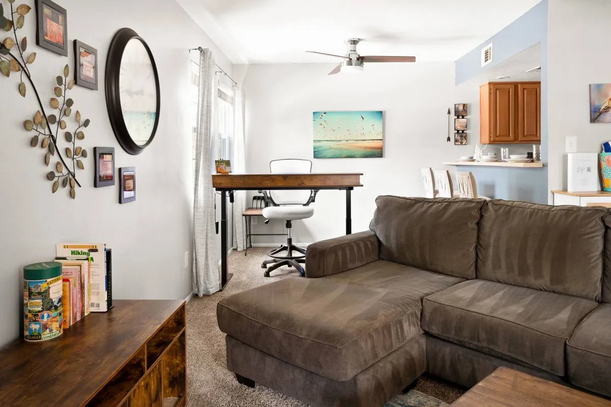 This image presents a comfortable sofa paired with a desk set against the wall, complemented by wall art and decorative leaves. It exudes a sense of comfort while highlighting the potential for both focused work and creative inspiration within the same space.